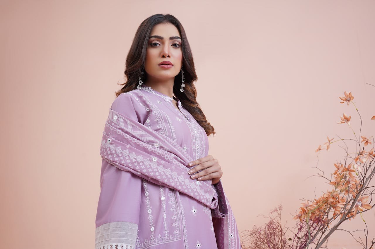 A woman wearing a traditional South Asian purple gown and posing indoors with floral decor.