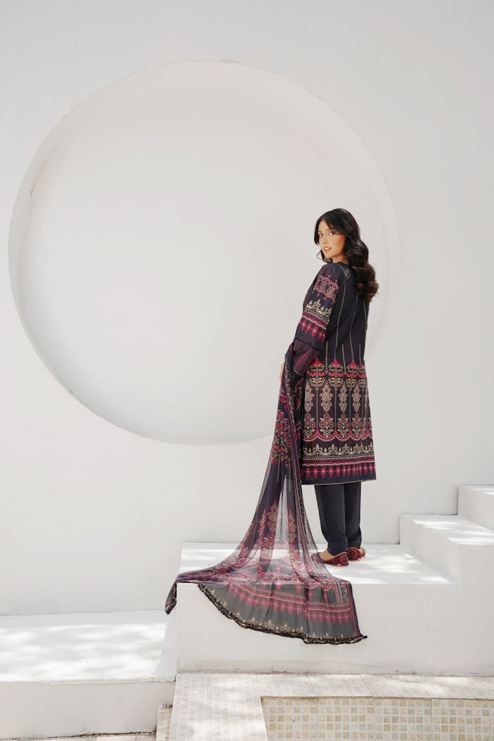 Fashion model in traditional Pakistani embroidered outfit posing outdoors.