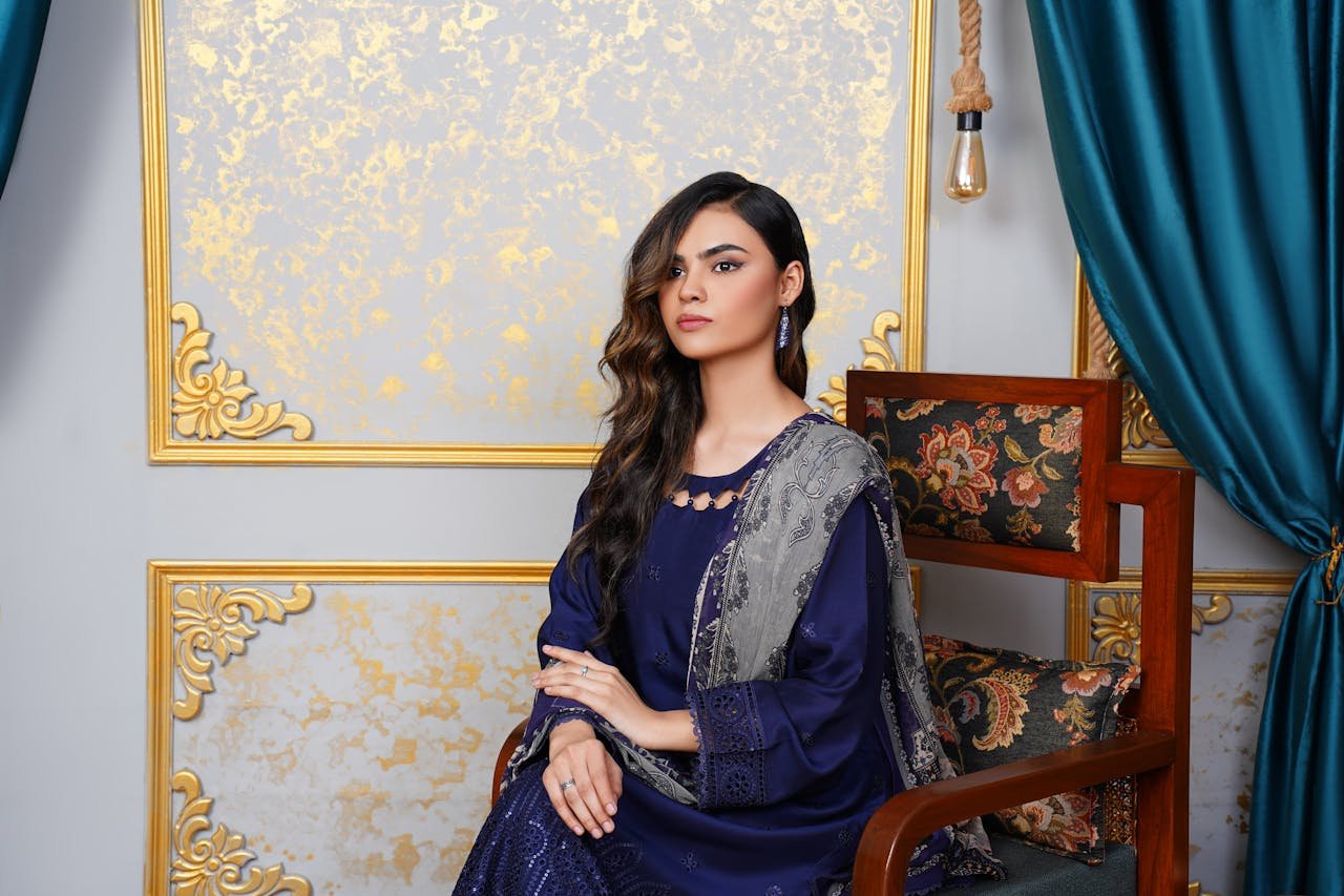 Elegant woman in traditional dress seated indoors with luxurious decor in Lahore, Pakistan.